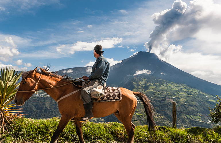 Homme sur un cheval devant le volcan Tungurahua, Équateur