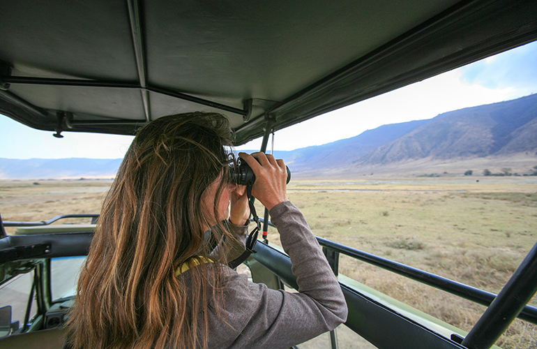 Randonneuse avec des jumelles regardant la faune depuis le 4X4, cratère de Ngorongoro, Safari, Tanzanie