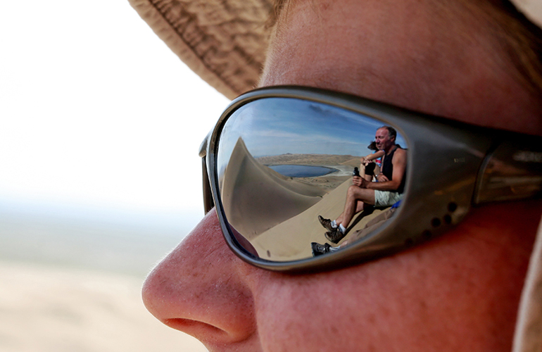 Reflet, dans un verre de lunette, de randonneurs sur une dune, Mongolie