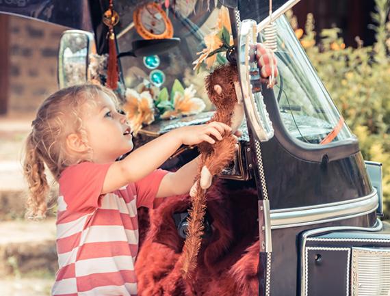 Petite fille examinant des jouets accrochés à un tuk-tuk au Sri Lanka.