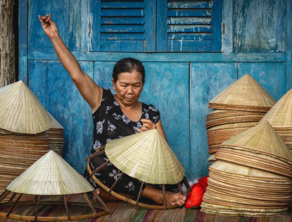 Vieille artisane vietnamienne fabriquant le chapeau traditionnel Nón Là dans l’ancienne maison traditionnelle du village d’Ap Thoi Phuoc, Ville de Ho Chi Minh, Vietnam