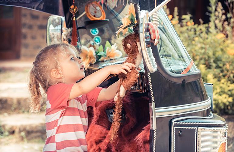 © Adobe Stock - plendens Petite fille examinant des jouets accrochés à un tuk-tuk au Sri Lanka.