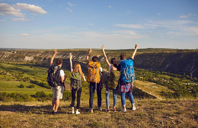 © Studio Romantic - Adobe Stock Groupe de marcheurs de dos face à un paysage verdoyant.
