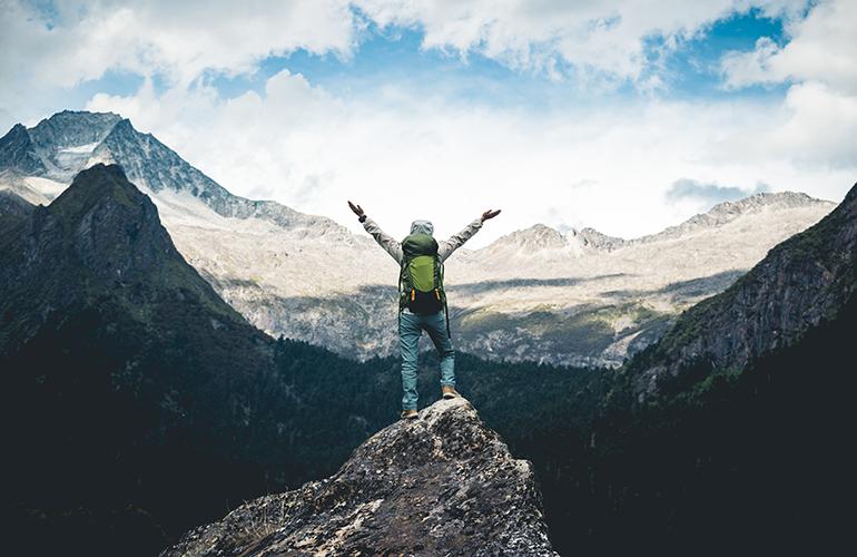 © izf - Adobe Stock Randonneuse heureuse devant un panorama de montagnes.
