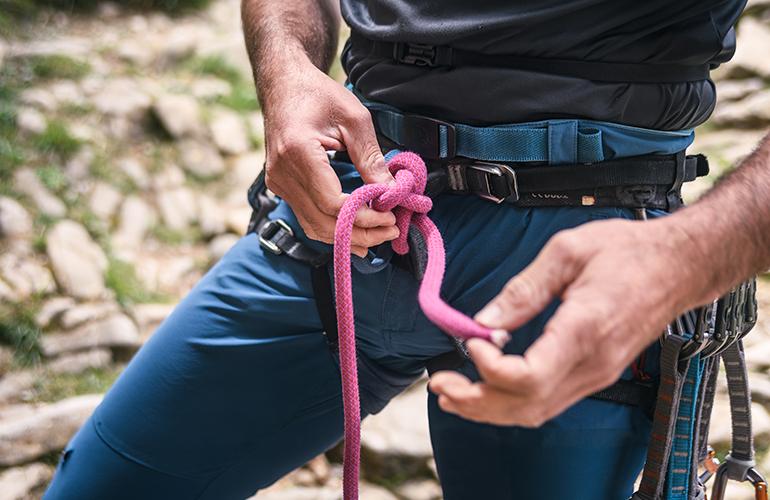 © EJManzaneque - Adobe stock Cadrage sur un homme réalisant un noeud pour escalader une paroi
