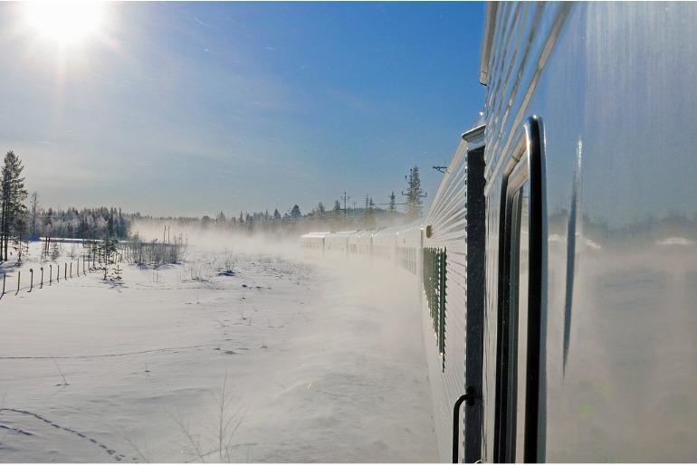 Un train suédois traverse des champs de neige étincelants au soleil, en Laponie