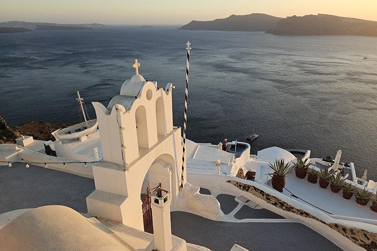 Chapelle à Oia avec vue sur la mer et les autres îles au coucher du soleil, Santorin, Cyclades, Grèce.